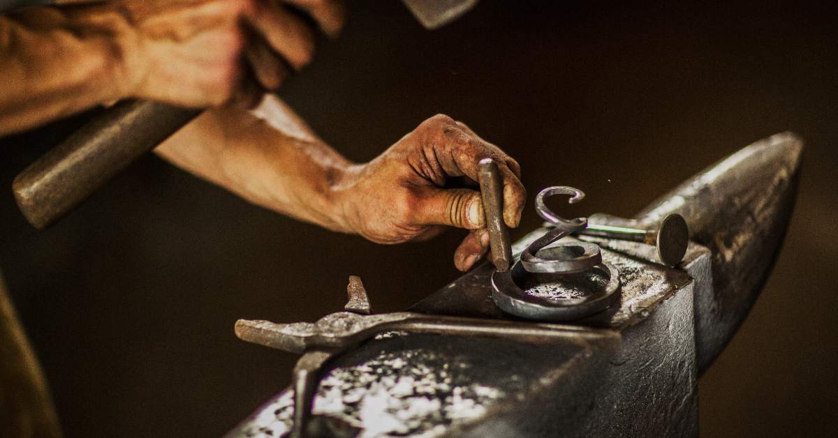 alt="Blacksmith working on an anvil"